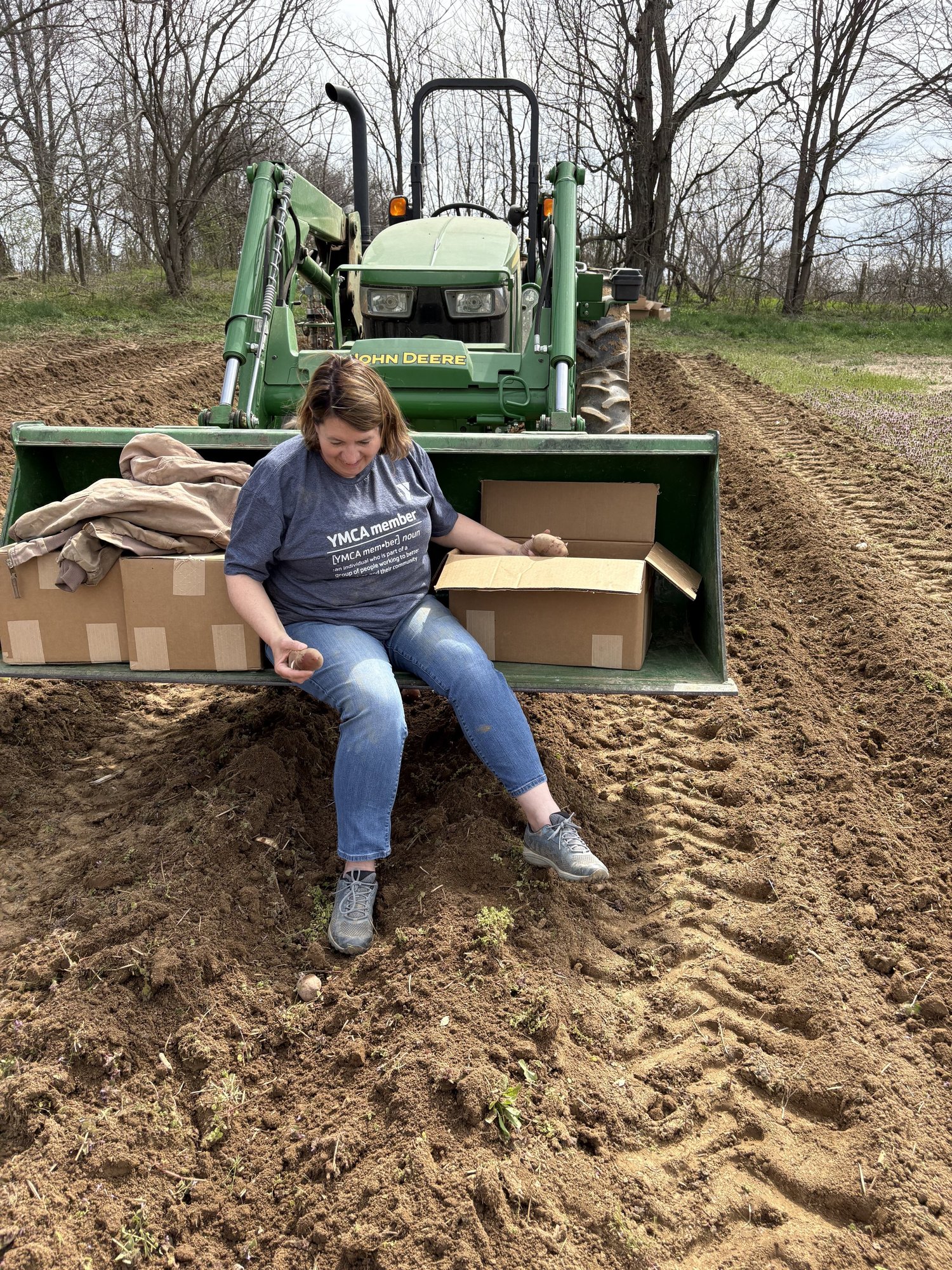 Sitting on the tractor bucket at the edge of a freshly worked field